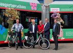 Fünf lächelnde Personen stehen mit 2 Fahrrädern vor einem Bus mit Folierung zur Landesgartenschau.